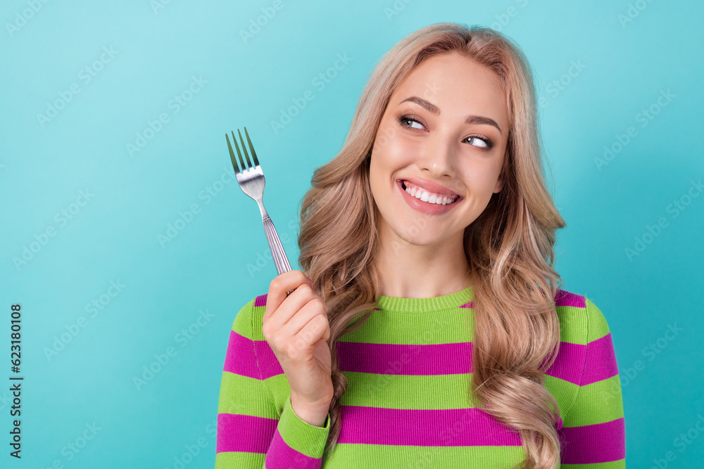 Portrait of optimistic cunning tricky girl wavy hairdo wear stylish clothes look at fork prepare to eat isolated on blue color background Portrait of optimistic cunning tricky girl wavy hairdo wear stylish clothes look at fork prepare to eat isolated on blue color background