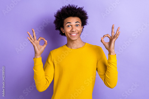 Portrait of positive friendly nice guy wear stylish yellow pullover two arms showing okey good job isolated on violet color background