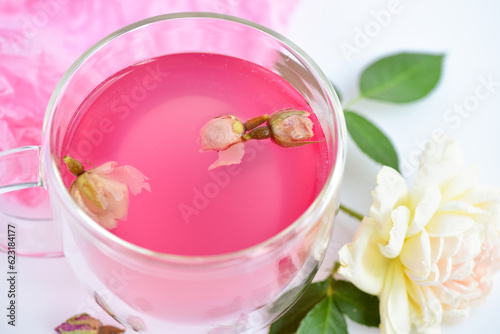 Close up a cup of roses tea with rose buds on white background