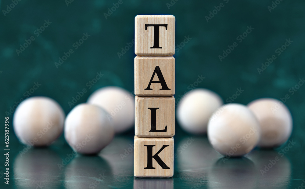 TALK - word on wooden cubes on a green background with wooden balls TALK - word on wooden cubes on a green background with wooden balls