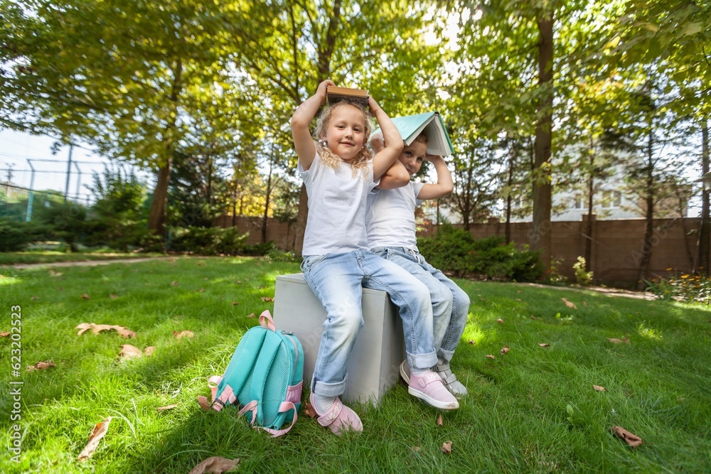 Fototapeta premium Schoolchilds hugging in park. Back to school concept.