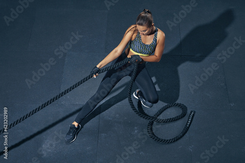 Power sporty female athlete exercising with rope at a gym top view photo