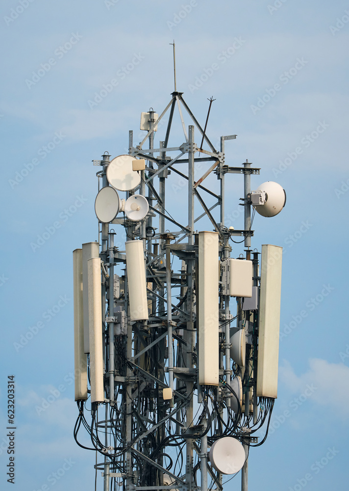 closeup of communication (cellular phone network) tower with antenna against backdrop of blue sky. Photo taken in suburban West Bengal.