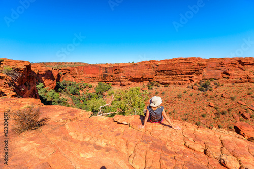 explorer woman with hat resting in Watarrka national park, Northern Territory NT, Australia. Tourist looking panorama of Kings Canyon in Red Center Outback.