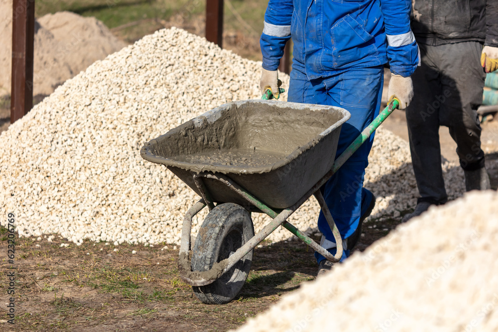 Workers are carrying a wheelbarrow with sand and cement Workers are carrying a wheelbarrow with sand and cement