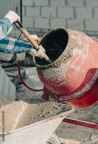 Obraz na plátne Worker pouring concrete with cement mixer at construction site, closeup