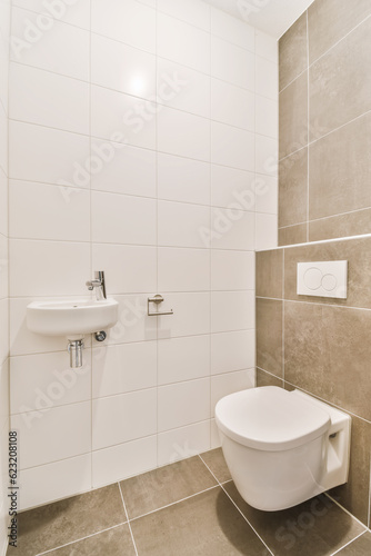 a white toilet and sink in a small bathroom with tiled walls, grey flooring and beige tiles on the wall