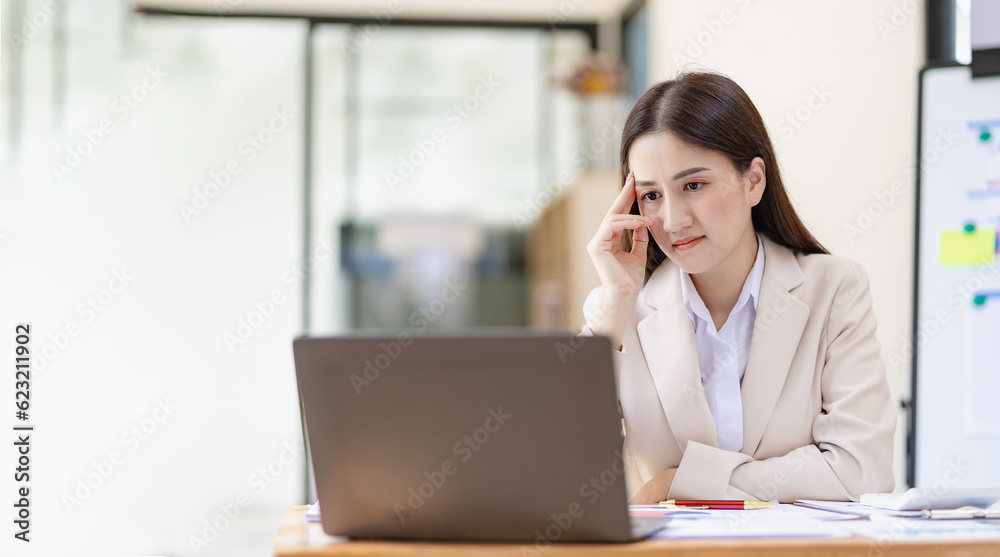 Asian female entrepreneur working in finance at home office analyzing financial graphs on documents with laptop on table in office Asian female entrepreneur working in finance at home office analyzing financial graphs on documents with laptop on table in office