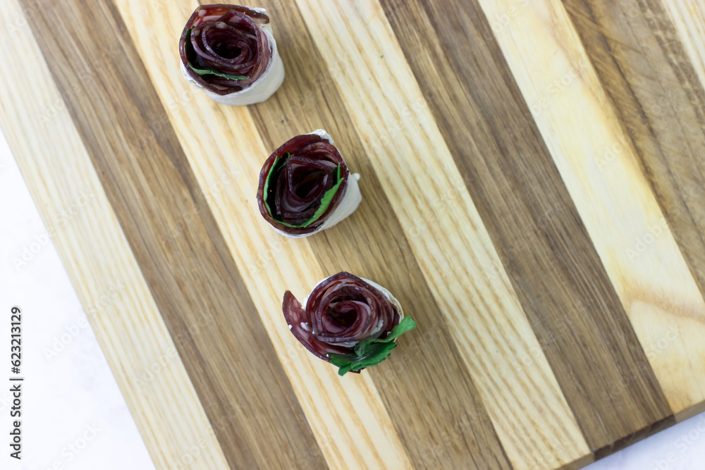 Festive snacks on a wooden board. Appetizers with sausage and cream cheese