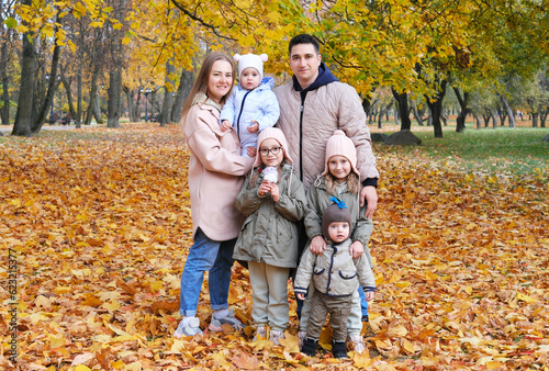 Large family posing in the autumn park. The family consists of mother, father and four children.