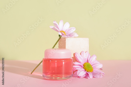 Jar of cosmetic product  plaster podium and flowers on color background