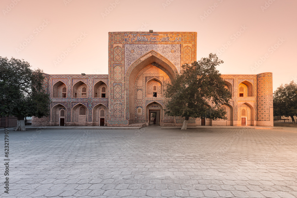 Facade of ancient madrasah decorated with traditional pattern in sunrise light, Bukhara, Uzbekistan