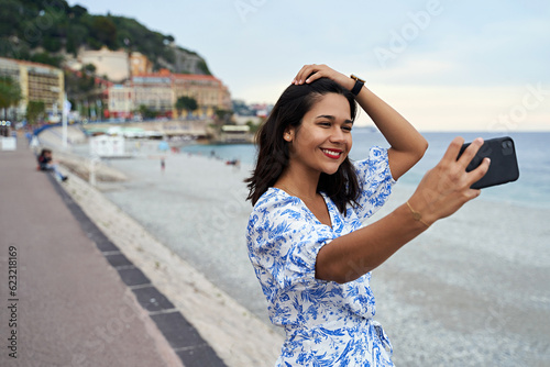 Beautiful smiling young woman takes selfie at the Promenade des Anglais in Nice, France