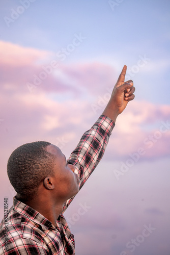 An inspirational photograph capturing the devotion of a Christian with clasped hands praying with the serene blue sky as a backdrop.