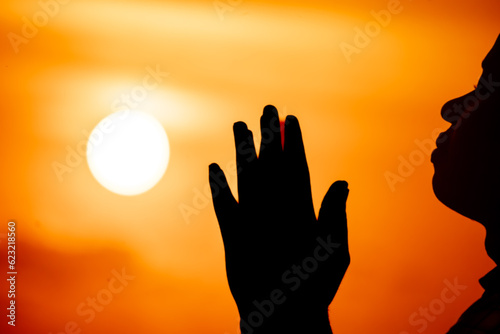 A captivating scene showcasing the silhouette of a man, arms outstretched to the sky, as he embraces the sunset of the solstice in a moment of deep prayer and devotion to Jesus.