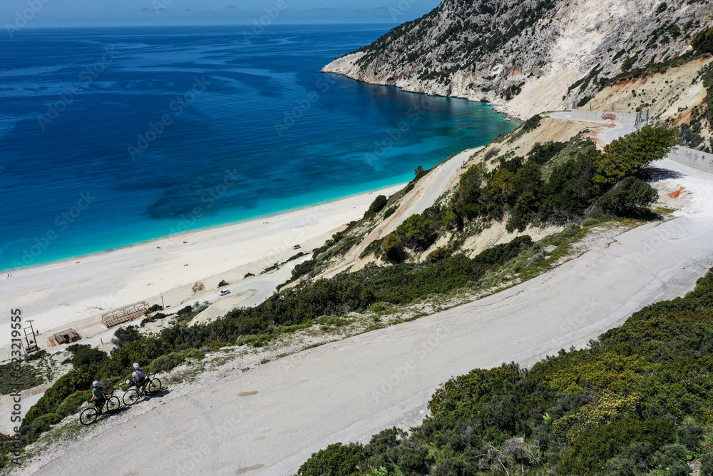 Drone photograph with cyclists on a scenic winding road above famous Myrtos Beach on the island of Kefalonia, Greece