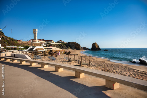 Wide panoramic view of the extensive sandy beach in Santa Cruz, Portugal, stretching along the Atlantic coastline next to a coastal town. 