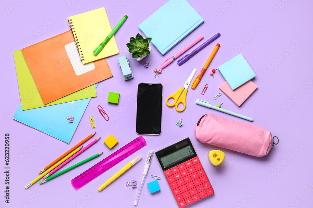 Different stationery with calculator and mobile phone on lilac background Different stationery with calculator and mobile phone on lilac background