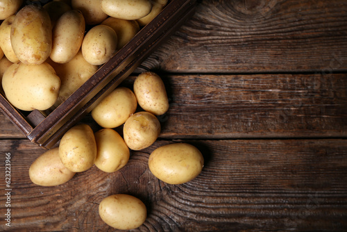 Box with raw potatoes on wooden table