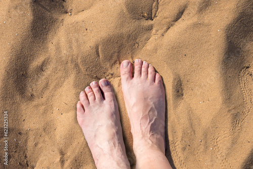 elderly womans feet at the hot sand, top view