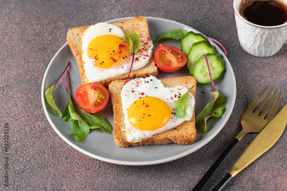 Heart-shaped fried eggs on toast with cherry tomatoes, cucumber and a cup of coffee for breakfast Heart-shaped fried eggs on toast with cherry tomatoes, cucumber and a cup of coffee for breakfast