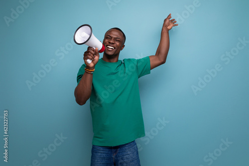 young attractive african man dressed in a basic t-shirt holding a loudspeaker to attract attention © Ivan Traimak