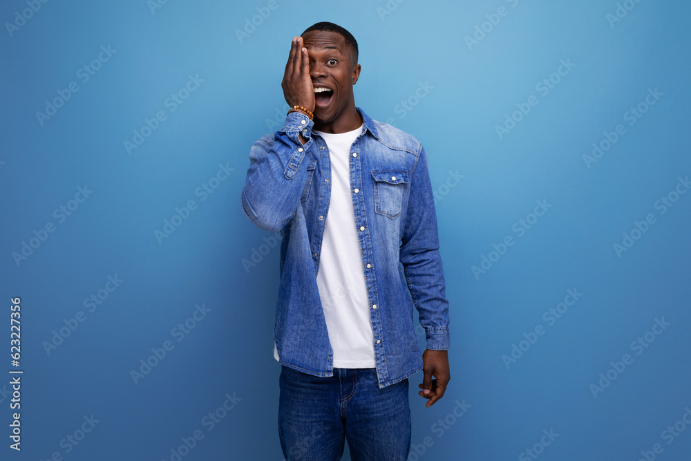 young energetic positive with dark skin american guy dressed stylishly in jeans smiling against the background with copy space young energetic positive with dark skin american guy dressed stylishly in jeans smiling against the background with copy space