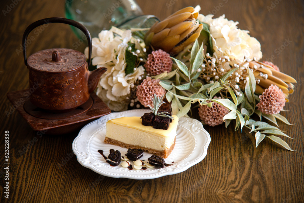 Fototapeta premium A piece of white cheese cake with some oreo biscuits and Chinese Tea pot