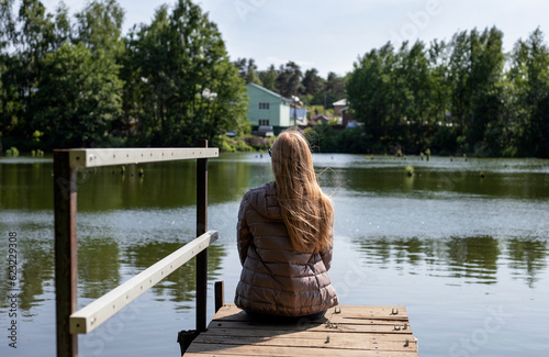 a girl with long red hair sits on a wooden bridge by the pond © Наталья Жукова