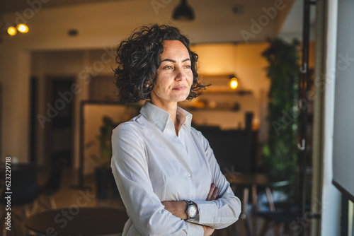 One woman mature caucasian female businesswoman entrepreneur stand at work or home real people copy space wear white shirt curly hair