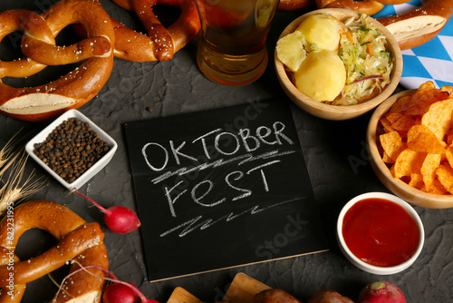 Different snacks and chalkboard with word OKTOBERFEST on black background