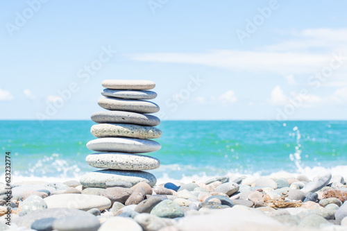 Pyramid stones balance on the beach next to the sea. Happy holidays. Pebble beach, calm sea, travel destination. Concept of happy vacation on the sea, meditation, spa, calmness.