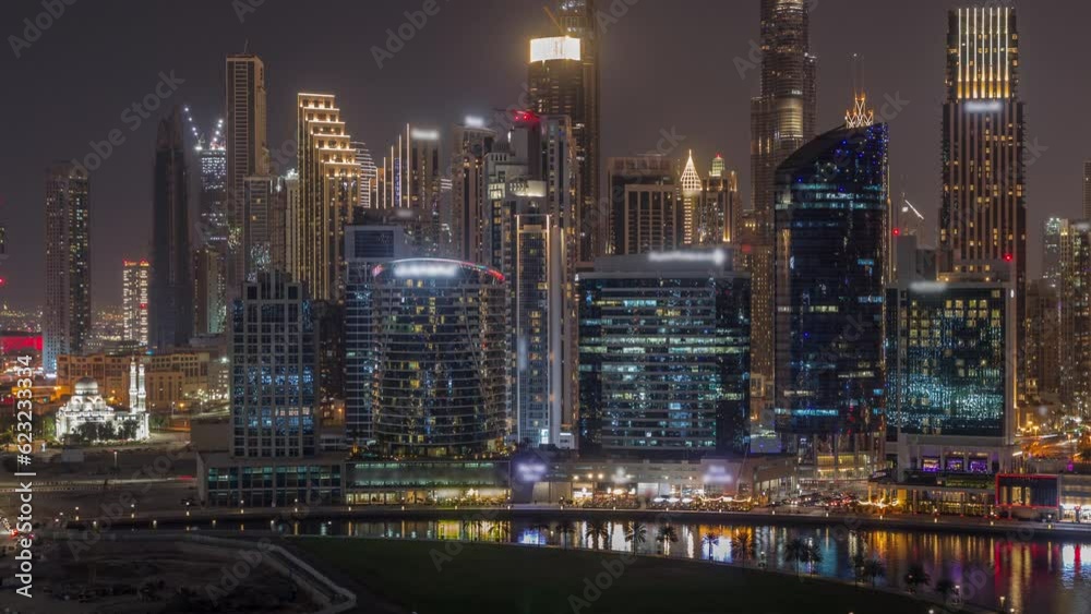Aerial view to Dubai Business Bay and Downtown with the various illuminated skyscrapers and towers along waterfront on canal night timelapse.