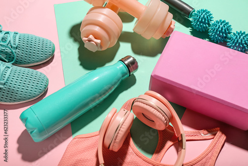 Composition with bottle of water, sports equipment and headphones on color background, closeup