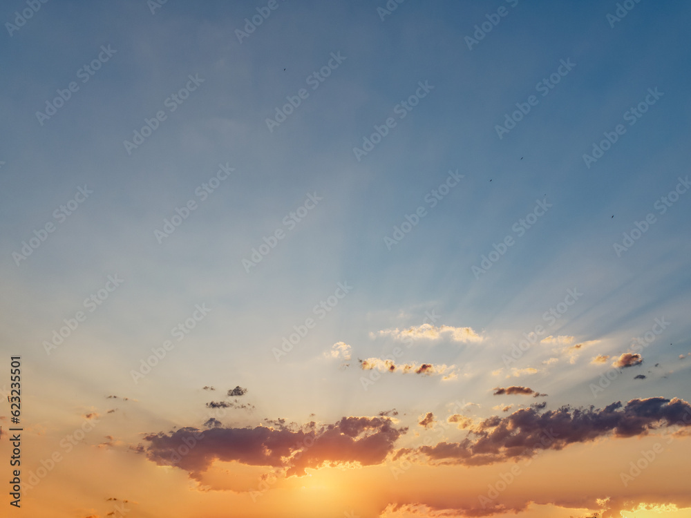 Dramatic sunset sky with god rays and color gradient, mostly clear sky with distant dark clouds