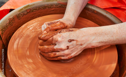 Clay pottery hands close up working on wheel handcrafts. Clay crockery making. Potter hands. Working with red clay.