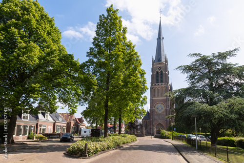 Street in the Dutch village of Sint Nicolaasga with a view of the medieval church Sint-Nicolaaskerk in Friesland.