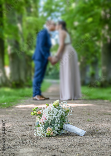 Wedding bouquet on foreground of a blurred kissing couple. Flowers and lovers