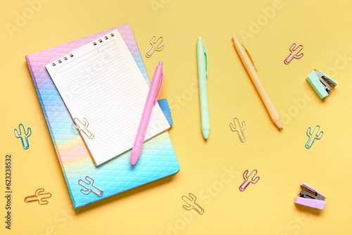 Different school stationery and blank notebook on yellow background