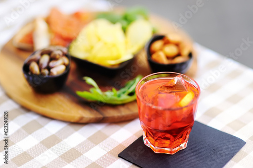 Italian aperitives/aperitif: glass of cocktail (sparkling wine with Aperol) and appetizer platter on the table photo