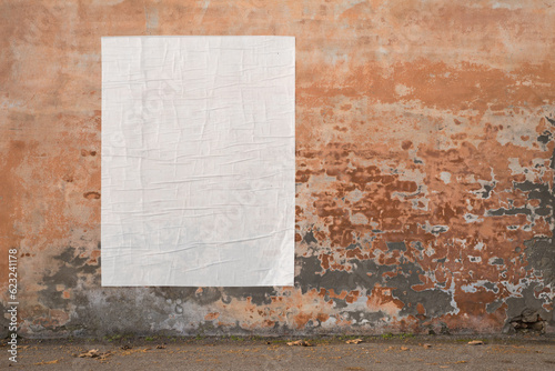 blank advertising poster glued to the weathered wall - copy space in pasted billboard on peeling plaster photo