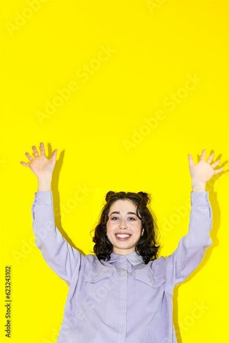 Happy latin woman with arms up - isolated over a yellow background