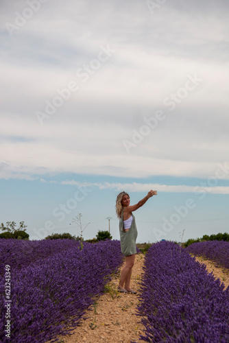 Wallpaper Mural Blonde woman with mobile phone in hand enjoying her summer vacation in a blooming field of lavenders Torontodigital.ca