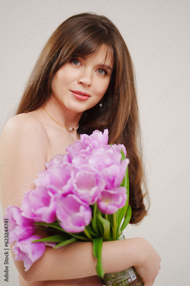 a gentle woman topless with tulips on a white background.