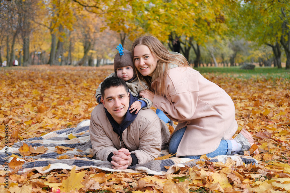 Family day in autumn park. Parents with son looking at camera and smiling Family day in autumn park. Parents with son looking at camera and smiling