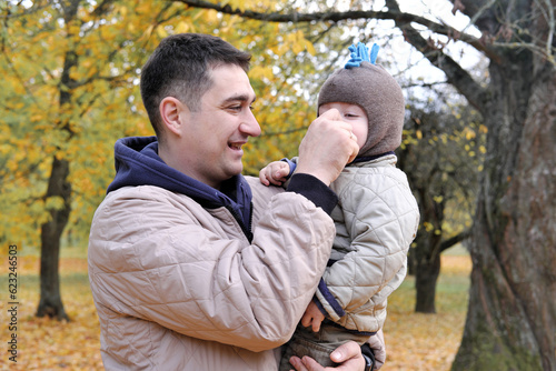 Dad and son spend time together in the autumn park. Father holding his son in his arms