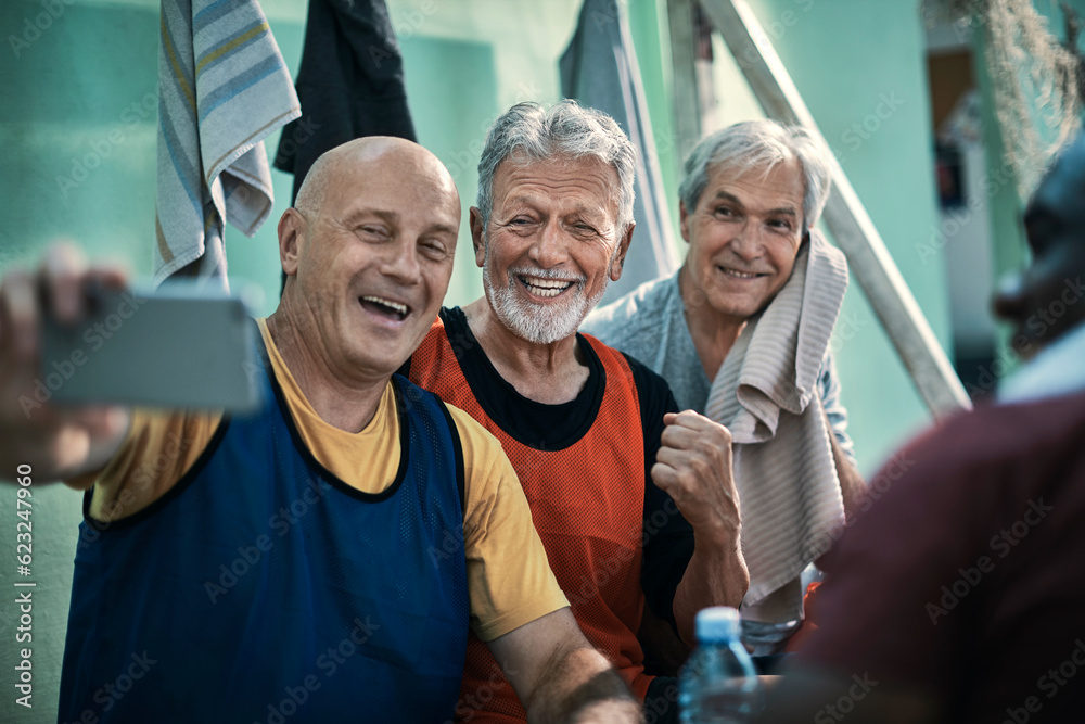 Senior men taking a selfie in the locker room after playing football Senior men taking a selfie in the locker room after playing football