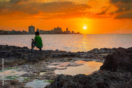 Photography Cuba, atardecer en el malecón de la Habana donde multitud de niños disfrutan del baño en las aguas del mar de la ciudad