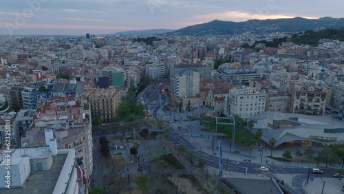Aerial slide and pan footage of modern square Placa de Lesseps with futuristic design library building. Hills against sunset sky in background. Barcelona, Spain photo