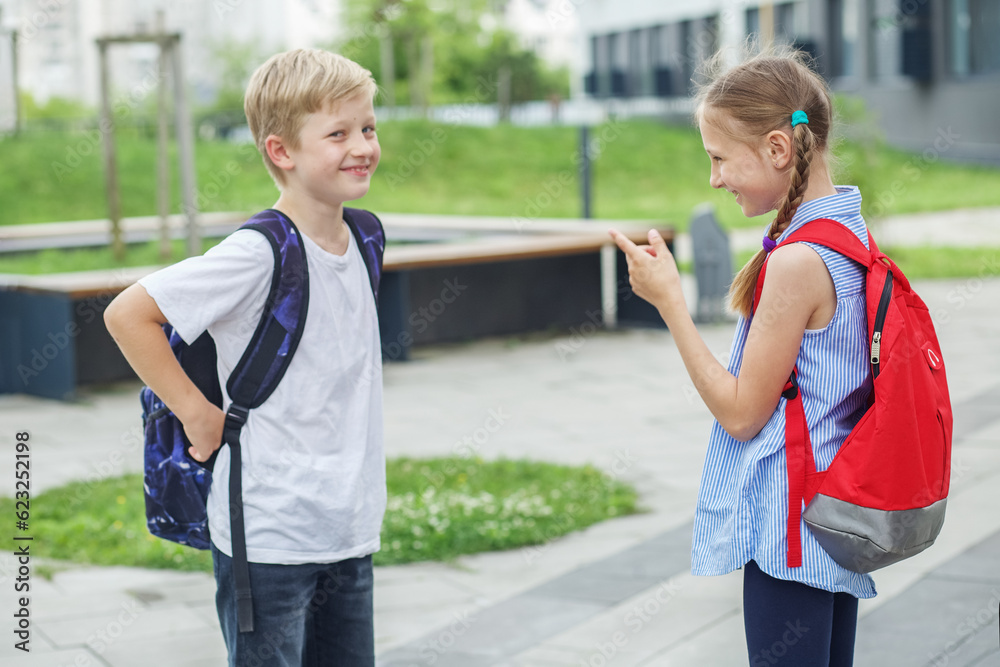 Naklejka premium Meeting friends. Back to school. Two children with backpacks met near school. Concept of learning